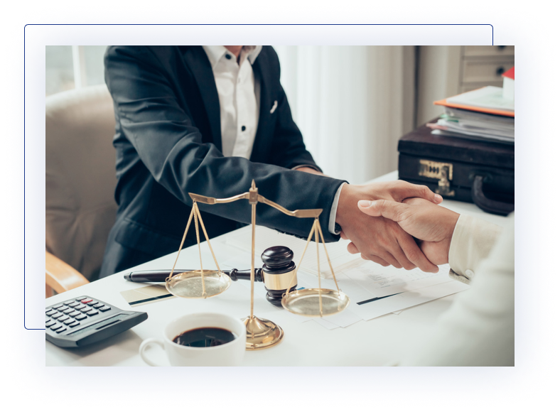 A lawyer and client shaking hands across a desk with legal items